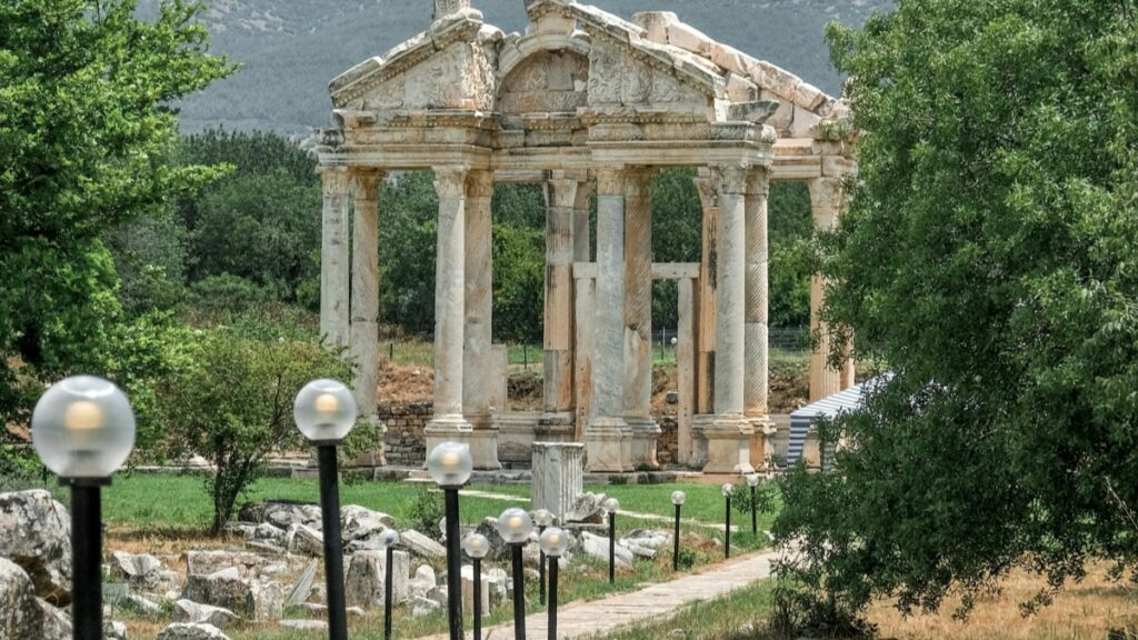 Μια αρχαία ελληνική τετραγωνική γωνιά με κολόνες και γλυπτικές.Alt text:"Τοιχογραφίες και κολόνες,η αρχαία Ελλάδα-Πώς να κερδίσετε χρήματα με ομάδες στο Facebook."